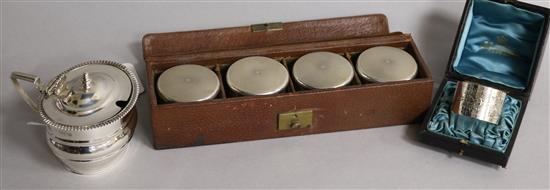 An Edwardian silver mustard, London, 1909, a cased set of four travelling silver mounted toilet jars and a cased silver napkin ring.